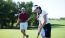 Two golfers on a PGA Parkway course, with a man observing in the background as a woman takes her shot. Offers unparalleled access to the premier golf courses along PGA Parkway.